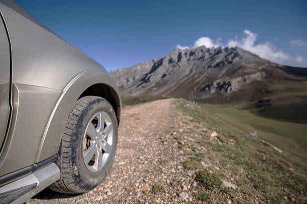 Close-up car tyre tracks on trail path in perspective. Off-road car wheels on a gravel road with defocused mountain in background, adventures, expedition, explore and travel suv. Close-up car tyre tracks on trail path in perspective. Haval H9 SUV stock pictures, royalty-free photos & images