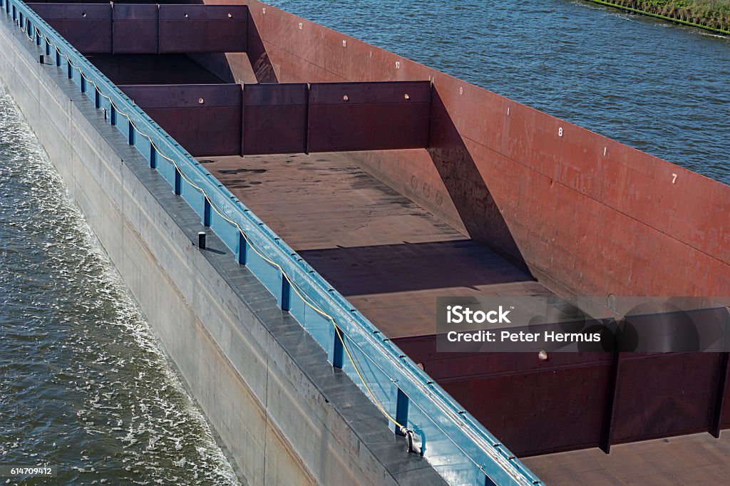 close up large empty cargo hold of freightship in Amsterdam Large empty freight ship in the Amsterdam - Rhine Canal, in the backdrop building site with cranes Cargo Hold Stock Photo