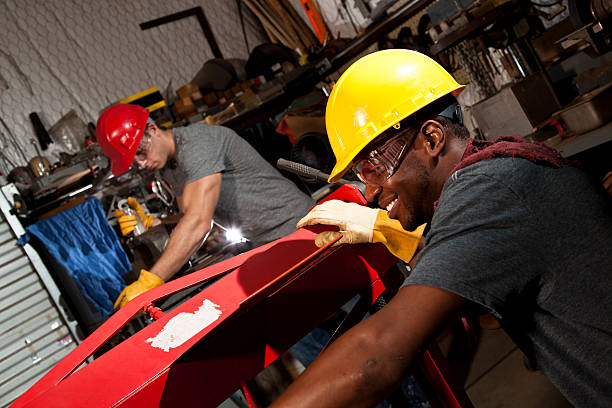 junge erwachsene mechaniker in kleinen unternehmen reparatur, werkstatt. - minority african ethnicity business hardhat stock-fotos und bilder