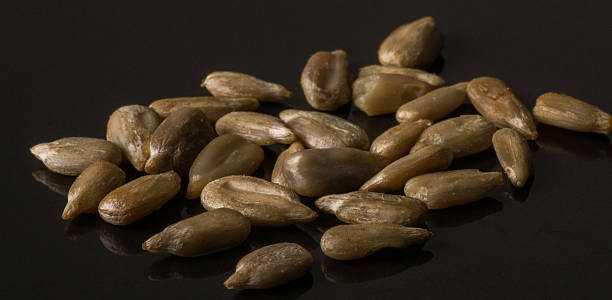 Shelled Sunflower Seeds on black Background Shelled Sunflower Seeds on black Background macro rapeseed shell stock pictures, royalty-free photos & images