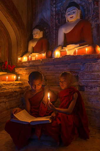 Two young buddhist monks praying inside the temple in Bagan, Myanmar