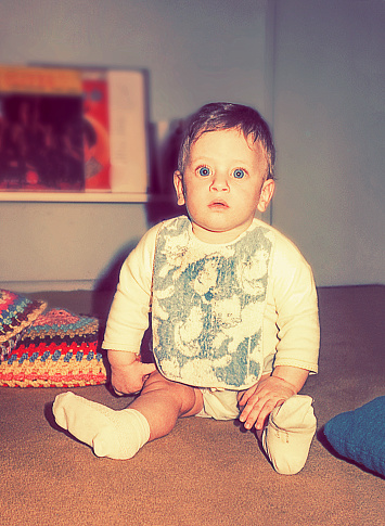 Vintage photo of a baby boy with big blue eyes looking at camera.