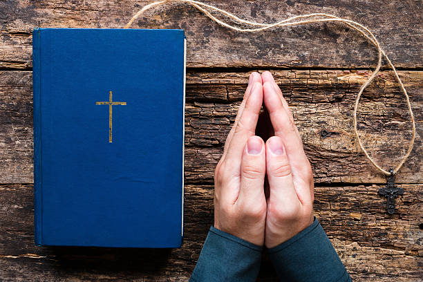istock man praying next to the bible and cross 614726476