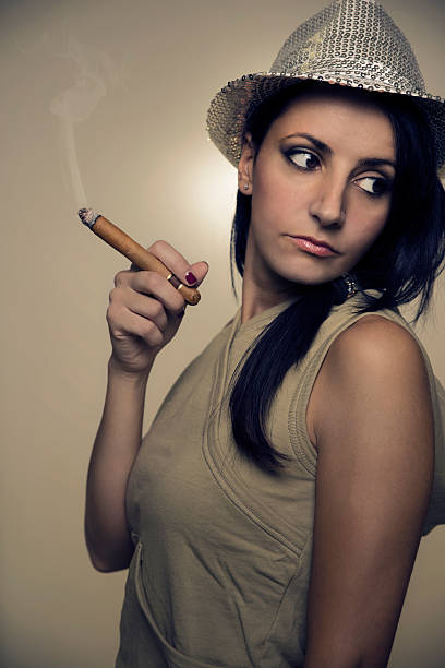 istock sensual woman with shiny hat smoking a cigar 614726664