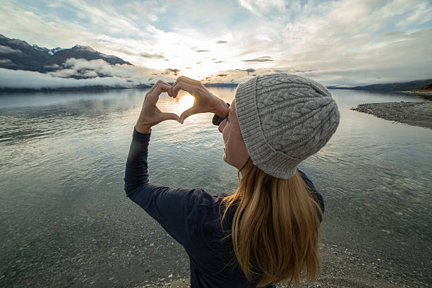 istock Young woman frames beautiful landscape into heart shape 614726730