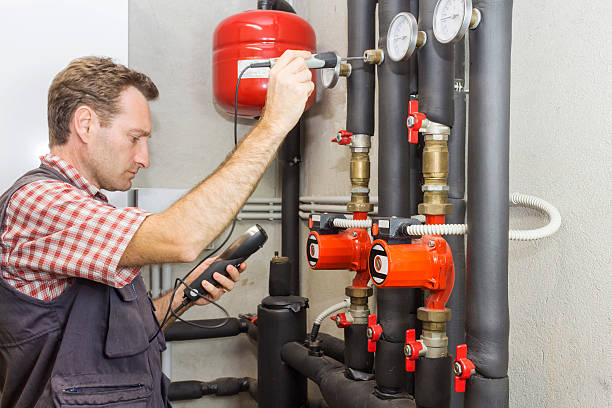 istock Plumber at  work measures the temperature in a boiler room 614728222