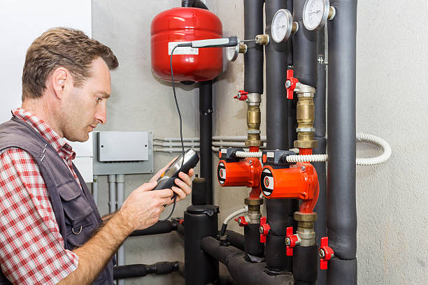 istock Plumber at  work measures the temperature in a boiler room 614728314