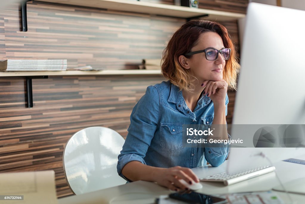 Working in a design studio Businesswoman looking at a computer in an office. Computer Stock Photo