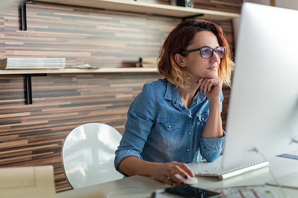 Working in a design studio Businesswoman looking at a computer in an office. freelance work stock pictures, royalty-free photos & images