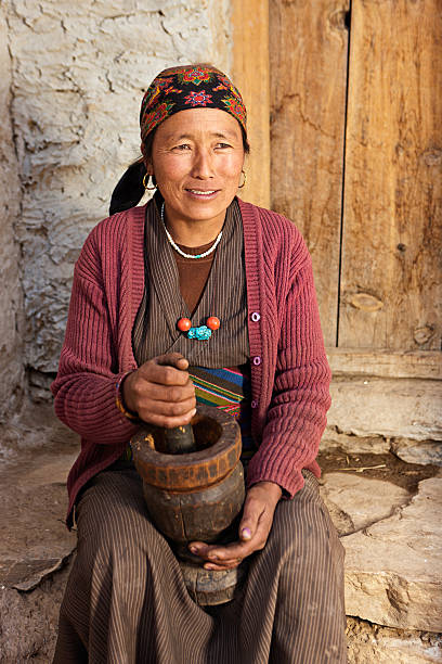 istock Tibetan woman using a mortar to make  flour. Mustang, Nepal 614737346