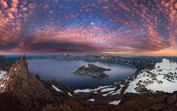 Man on hilltop viewing Crater Lake with full moon