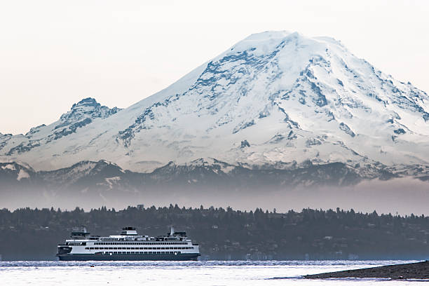 Mount Rainier Looms over Ferry on Puget Sound Washington State car and passenger ferry crossing Puget Sound. Mount Rainier looms large in the background. bainbridge island photos stock pictures, royalty-free photos & images