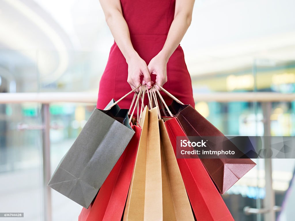 young woman carrying paper shopping bags in modern mall young woman female shopper standing with colorful paper bags in hands in shopping mall or department store, focus on hands Shopping Bag Stock Photo