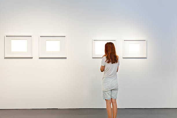 istock One woman looking at white frames in an art gallery 614746034
