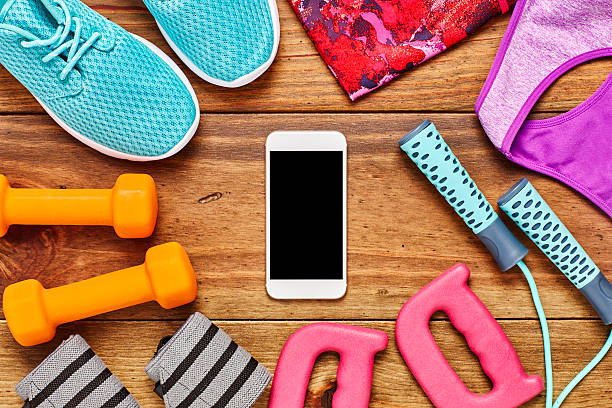 istock Smart phone surrounded with sports equipment on floor 614746048