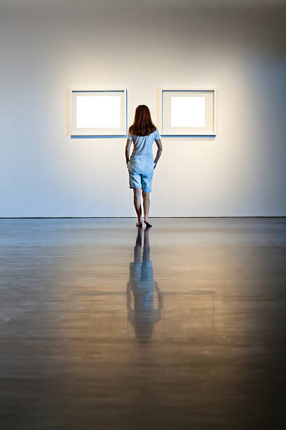 istock One woman looking at white frames in an art gallery 614746098