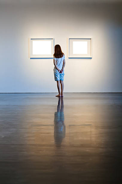 istock One woman looking at white frames in an art gallery 614746118