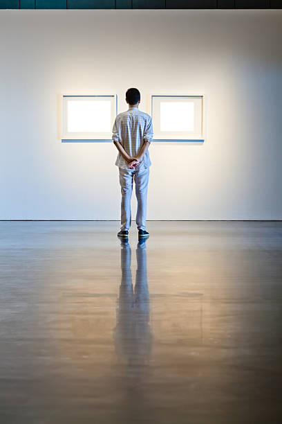 istock One man looking at white frames in an art gallery 614746218