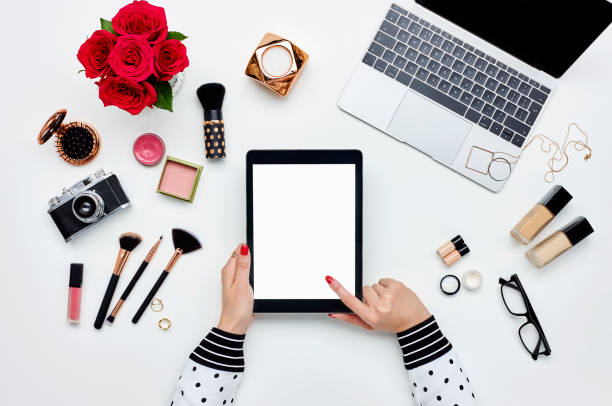 Woman using digital tablet surrounded with beauty products and technologies
