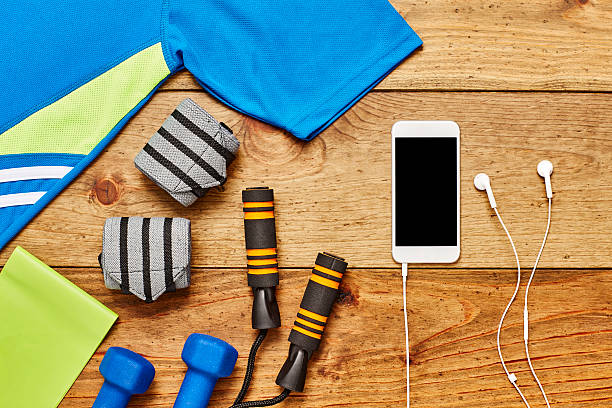 istock Smart phone with headphones and exercise equipment on wood 614748034