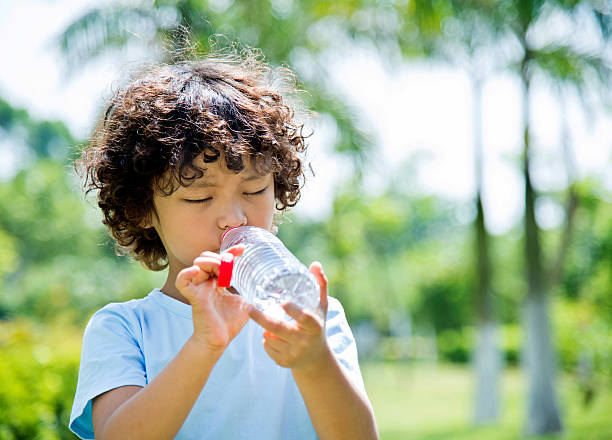 istock Young asian boy drinking water outdoors 614748262