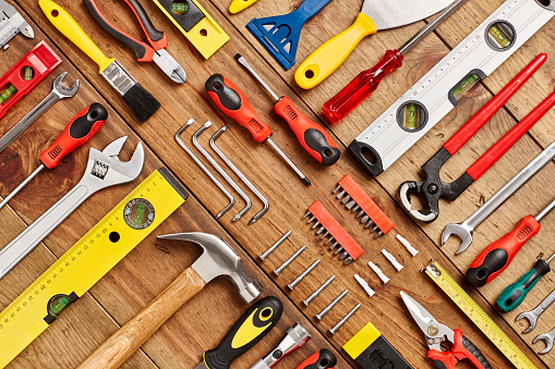 Full frame shot of various hand tools. Directly above flat lay shot of carpentry equipment diagonally arranged on wooden floor. They are representing the concept of DIY. Knolling concept.