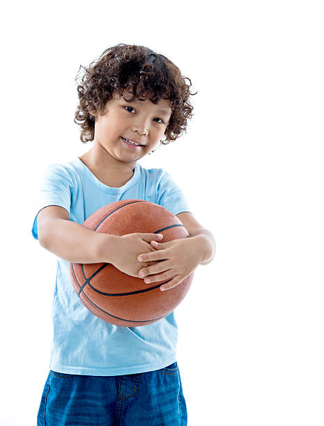 istock Young boy holding a basketball against white background 614833586
