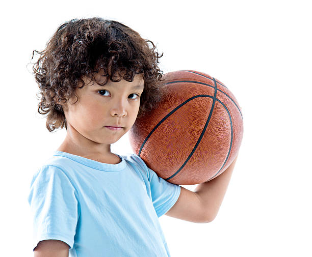 istock Young boy holding a basketball against white background 614834080