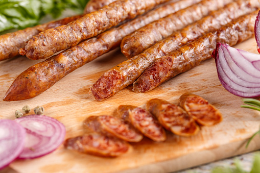 Smoked thin sausage salami slices on wooden cutting board