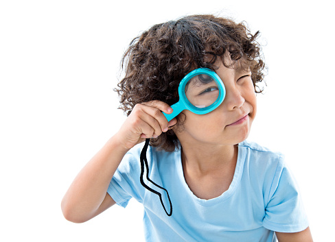 Little boy holding magnifying glass against white background.