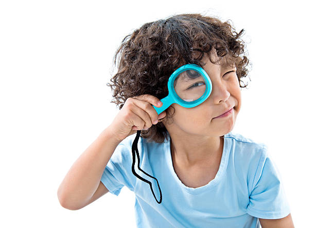 little boy holding magnifying glass against white background - searching child curiosity discovery imagens e fotografias de stock