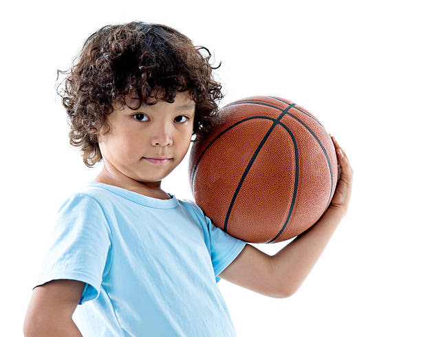 istock Young boy holding a basketball against white background 614834324