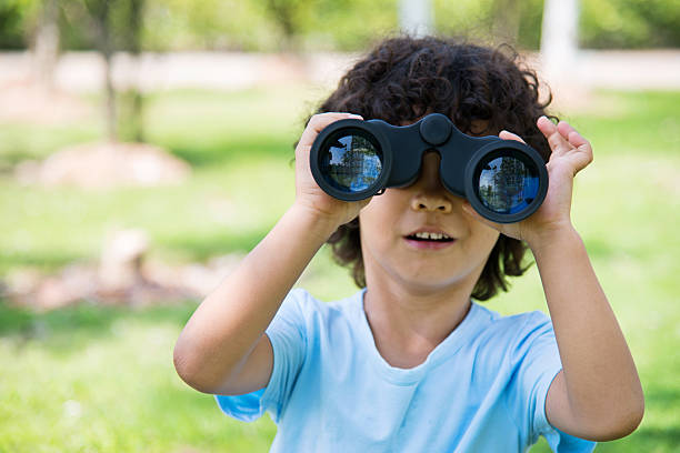 istock Little boy holding a binocular at park 614834456