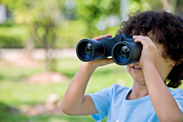 istock Little boy holding a binocular at park 614834632