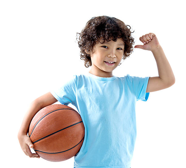 istock Young boy holding a basketball against white background 614834702