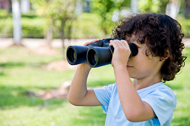 istock Little boy holding a binocular at park 614834800