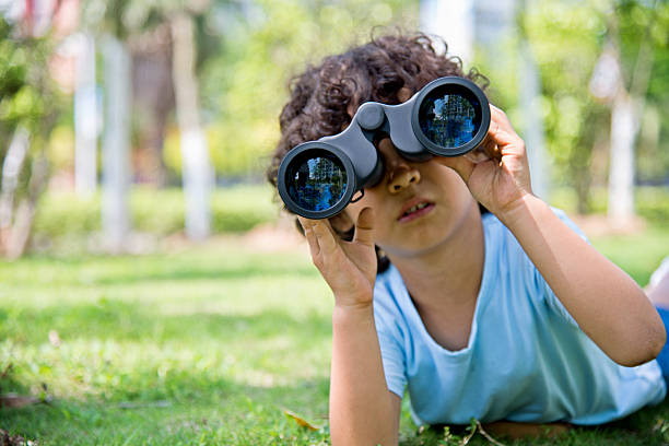 istock Little boy holding a binocular at park 614835228
