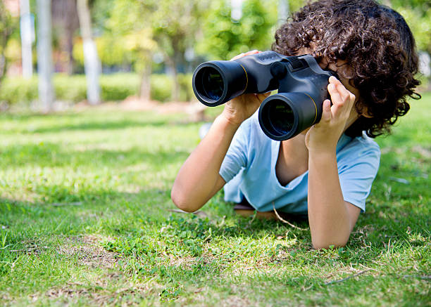 istock Little boy holding a binocular at park 614835576