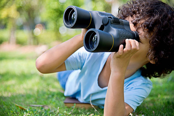 istock Little boy holding a binocular at park 614835904