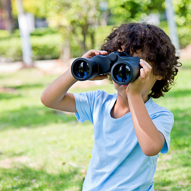 istock Little boy holding a binocular at park 614836426
