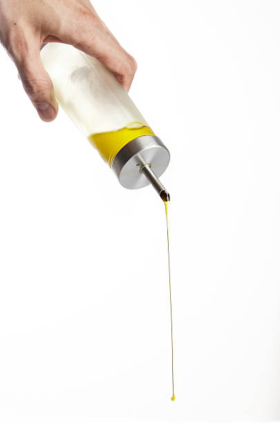 istock Hand Pouring olive oil from glass bottle on white background 614838624