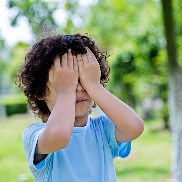 istock Little asian boy covering eyes in a park 614839906