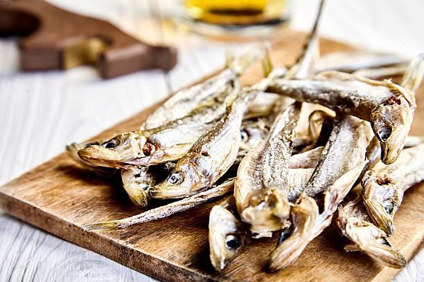 istock Dried fish on chopping board, mug of beer behind 614840304