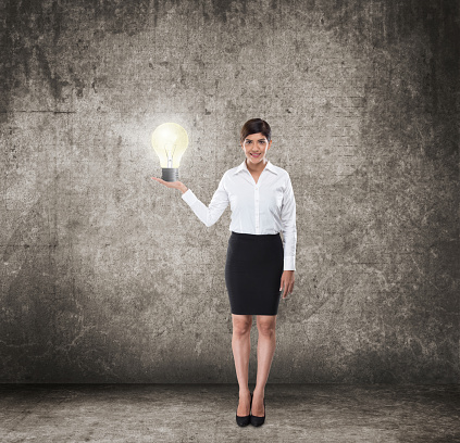 Young businesswoman standing and holding light bulb