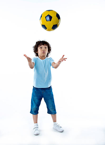 Little boy playing football against white background.