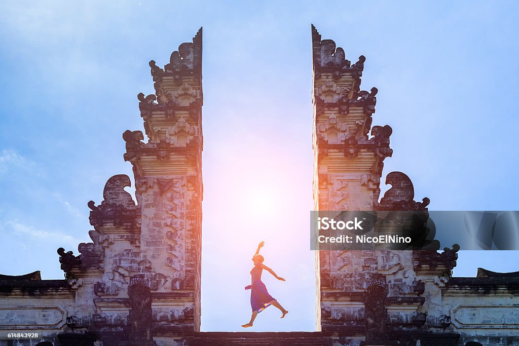 Woman traveler jumping with energy in gate temple, Bali, Indonesia Woman traveler jumping with energy and vitality in the gate of a temple, Bali, Indonesia Bali Stock Photo