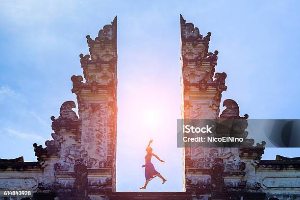 Woman Traveler Jumping With Energy In Gate Temple Bali Indonesia Stock Photo - Download Image Now