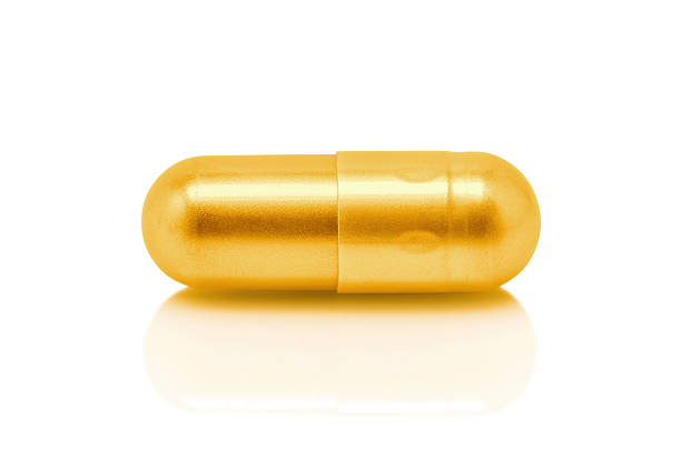 istock Gold pill capsule isolated on white background 614846196