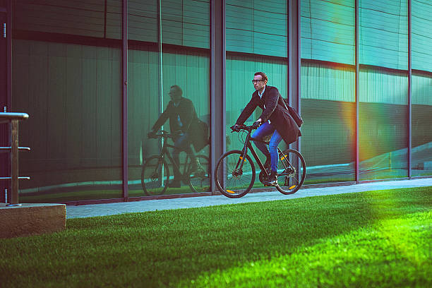 istock Handsome man riding bicycle beside the modern office building 614850478