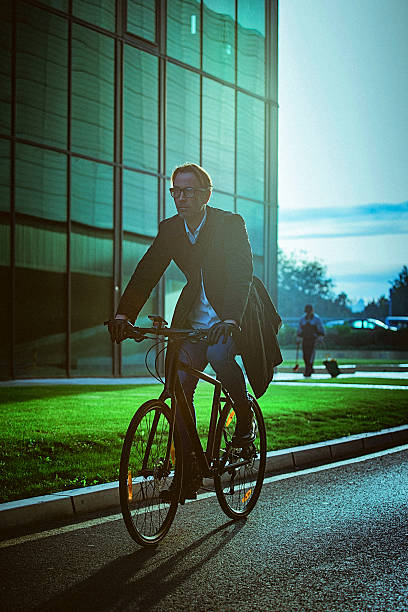 istock Handsome man riding bicycle beside the modern office building 614851260